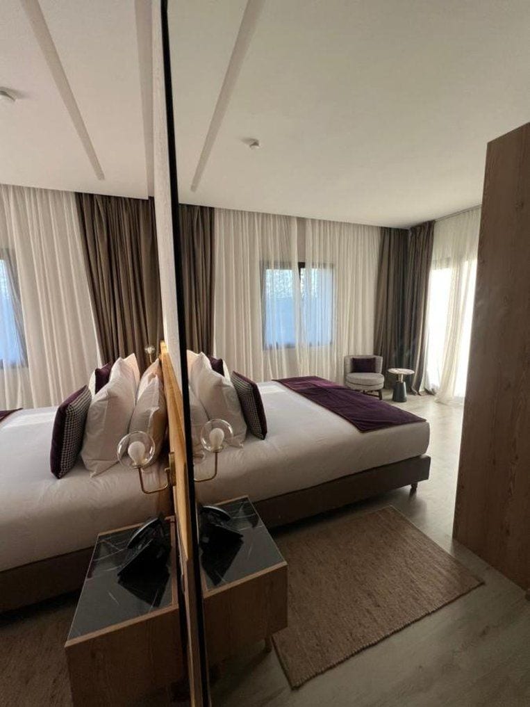 Ein modernes Hotelzimmer mit einem großen Bett, einem kleinen Tisch und einem Spiegel.