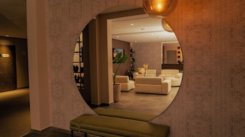 A circular mirror reflecting a modern living room with sofas, a plant, and a bench.