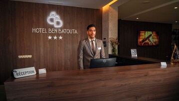 A hotel reception desk with a sign reading 'HOTEL BEN BATOUTA' and a 'RECEPTION' sign.