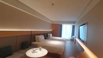 A modern hotel room with a large bed, a sofa, a small table, and a TV.