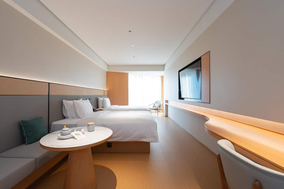 Quarto de hotel moderno com cama, mesa de cabeceira e televisão na parede.