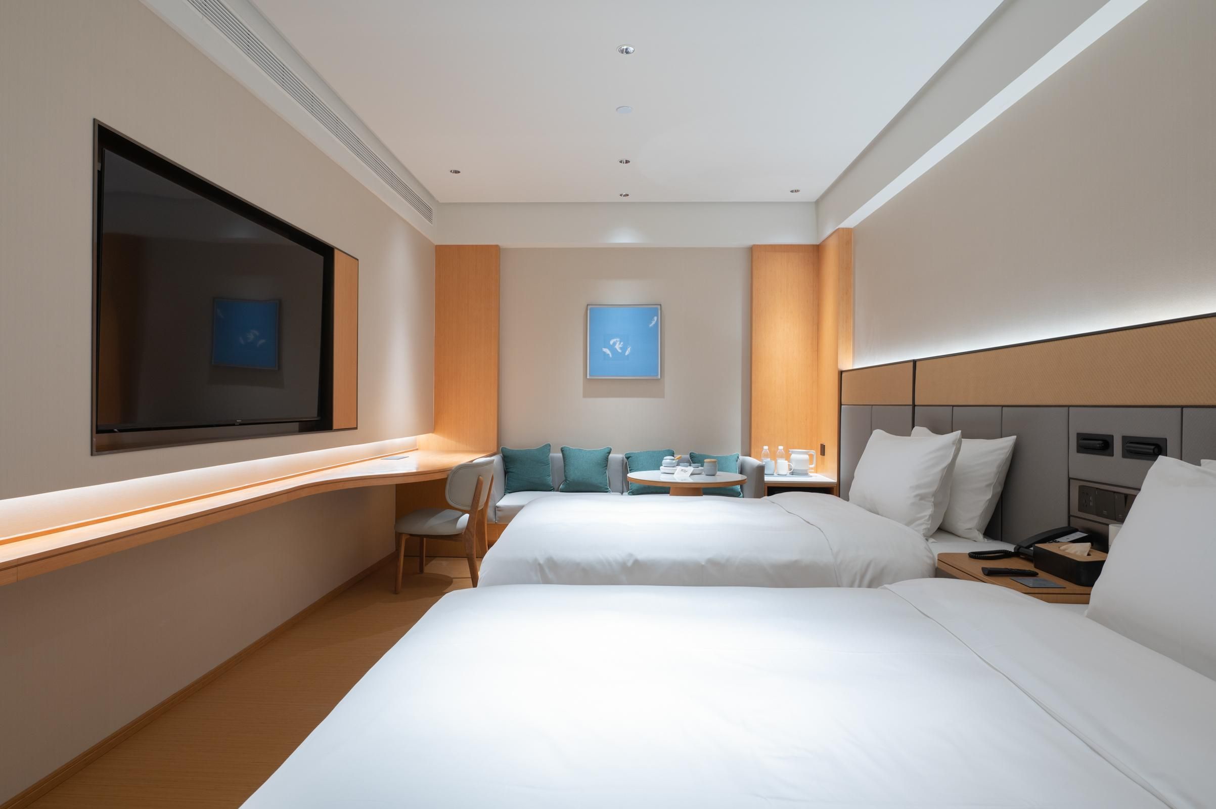 Une chambre d’hôtel avec deux lits, un bureau, une chaise, une télévision et une petite table avec une lampe.