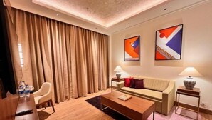 A modern hotel room with a wooden coffee table, a sofa, a TV, and a large window with curtains. - Vivanta Tawang Arunachal Pradesh (Tawang)