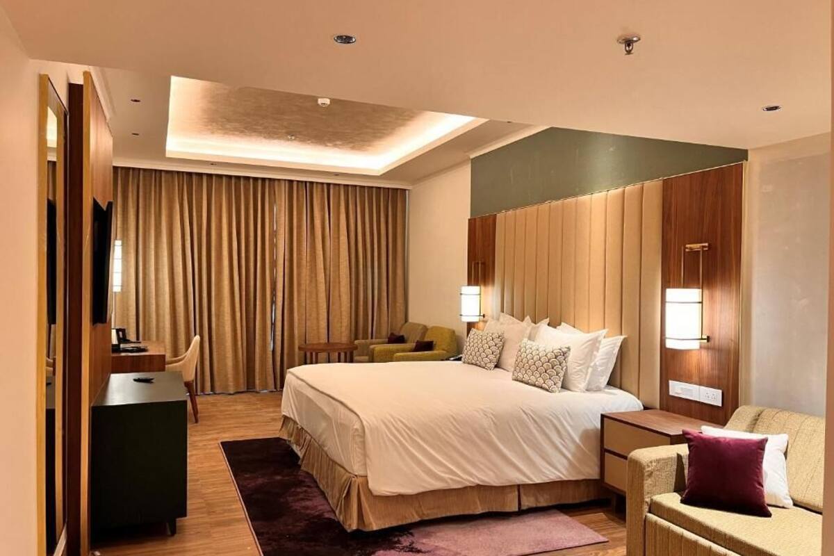 Ein modernes Hotelzimmer mit einem großen Bett, einem Schreibtisch, einer Couch und einem Fernseher.