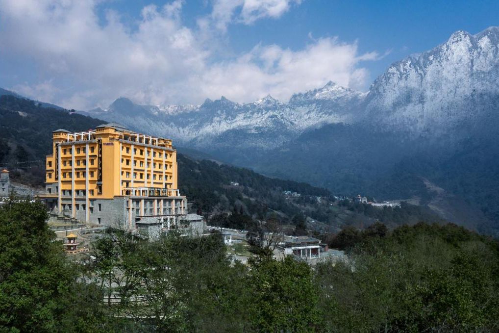 Een hotel met meerdere verdiepingen, met een geel gevel, gelegen voor een achtergrond van met sneeuw bedekte bergen en een heldere lucht.