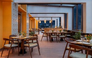 Een restaurant met meerdere eettafels, stoelen en een bar.