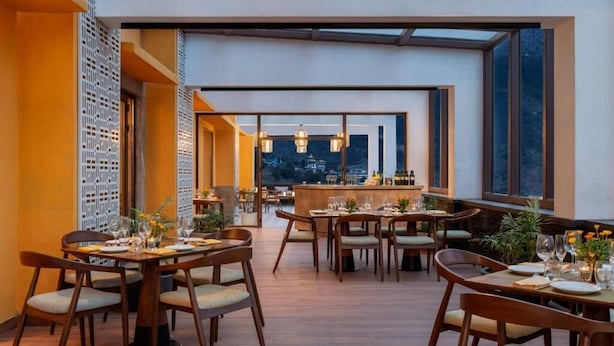 A restaurant with multiple dining tables, chairs, and a bar area. - Vivanta Tawang Arunachal Pradesh (Tawang)