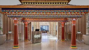 A hotel lobby with a central reception desk, wooden pillars, and a colorful ceiling design. - Vivanta Tawang Arunachal Pradesh (Tawang)
