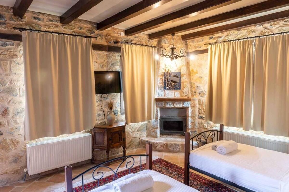 A cozy room with stone walls, a fireplace, two beds, and a TV.