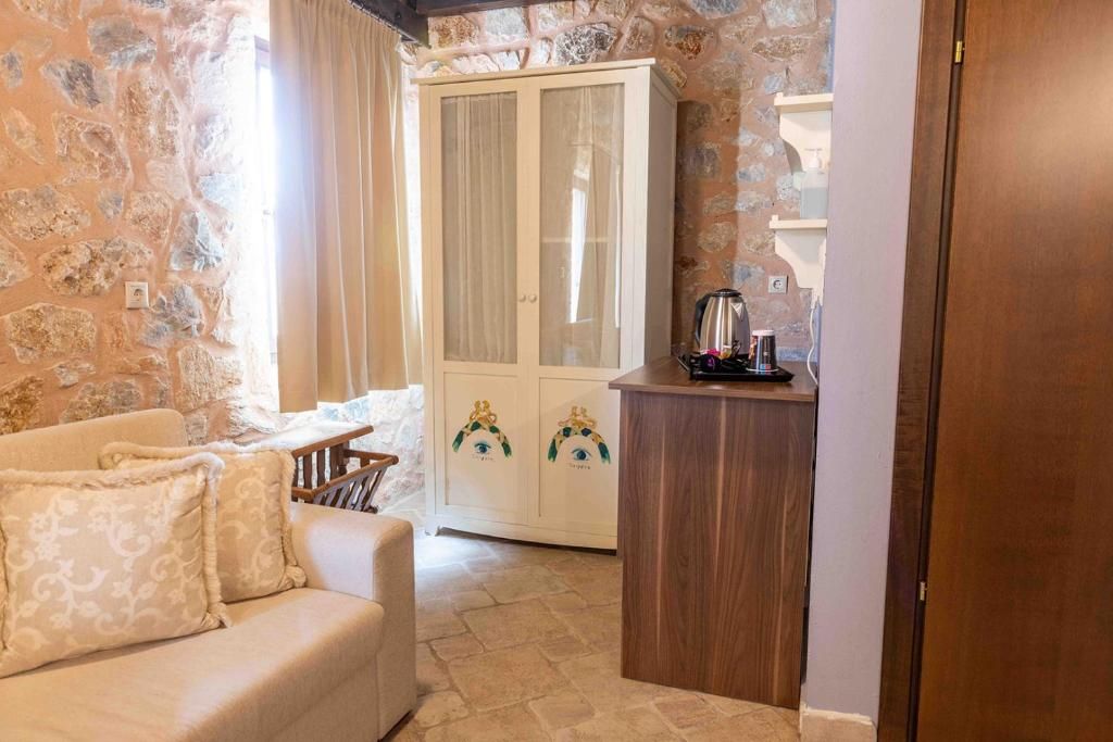 A cozy room with a sofa, a cabinet with decorative items, and a stone wall.