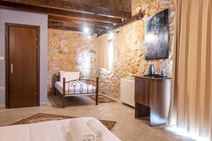 A bedroom with a stone wall, a wooden bed, a bedside table, and a radiator. - Lithea Mountain Resort And Spa (Florina)