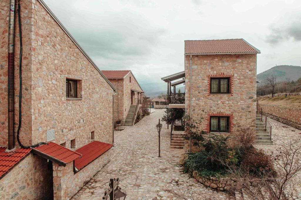 A stone building with a red-tiled roof, a staircase, and a cobblestone pathway.