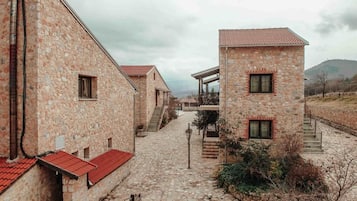A stone building with a red-tiled roof, a staircase, and a cobblestone pathway.
