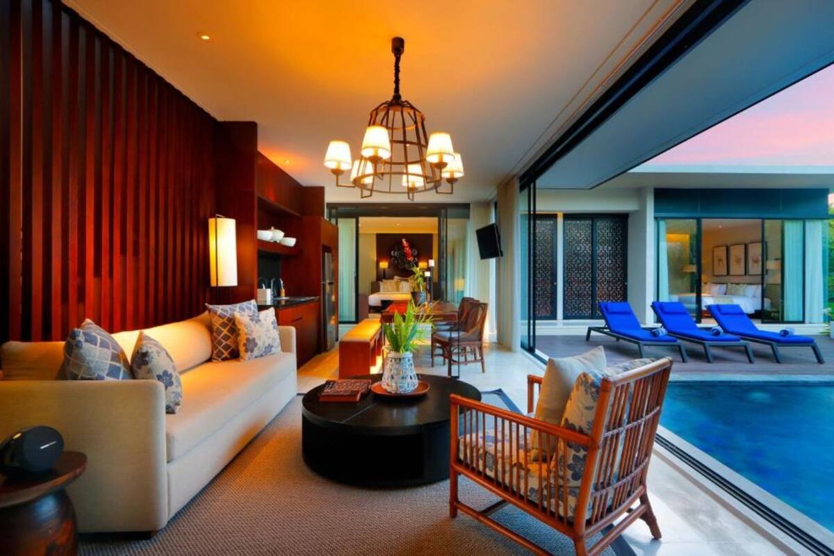 A modern living room with a sofa, coffee table, and a poolside area with lounge chairs.