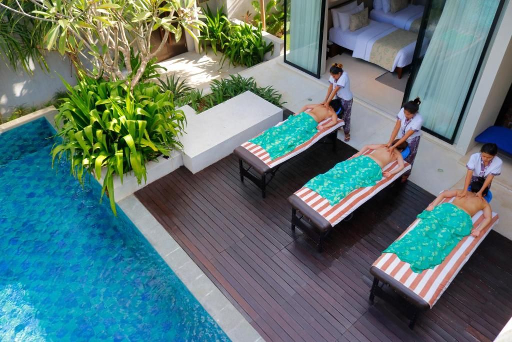 A poolside massage area with three massage tables, a pool, and a bedroom with a bed and curtains.