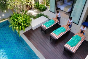 A poolside massage area with three massage tables, a pool, and a bedroom with a bed and curtains. - Vinila Villas (Nusa Dua)