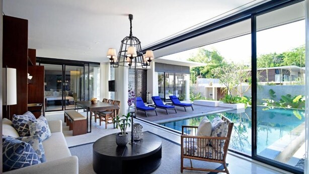Ein modernes Wohnzimmer mit Pool, Essbereich und Blick ins Freie.
