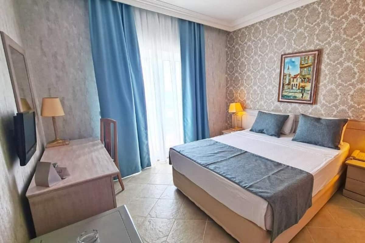 Ein Hotelzimmer mit Bett, Nachttischen, Schreibtisch und Stuhl.