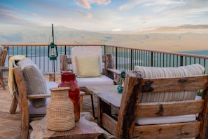 A terrace with wooden furniture, a lantern, and a view of distant mountains. - Ngorongoro Lodge Melia Collection (Ngorongoro)