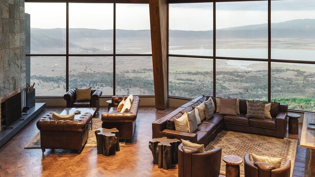 A spacious living room with a large window overlooking a scenic landscape, furnished with leather sofas and a fireplace. - Ngorongoro Lodge Melia Collection (Ngorongoro)
