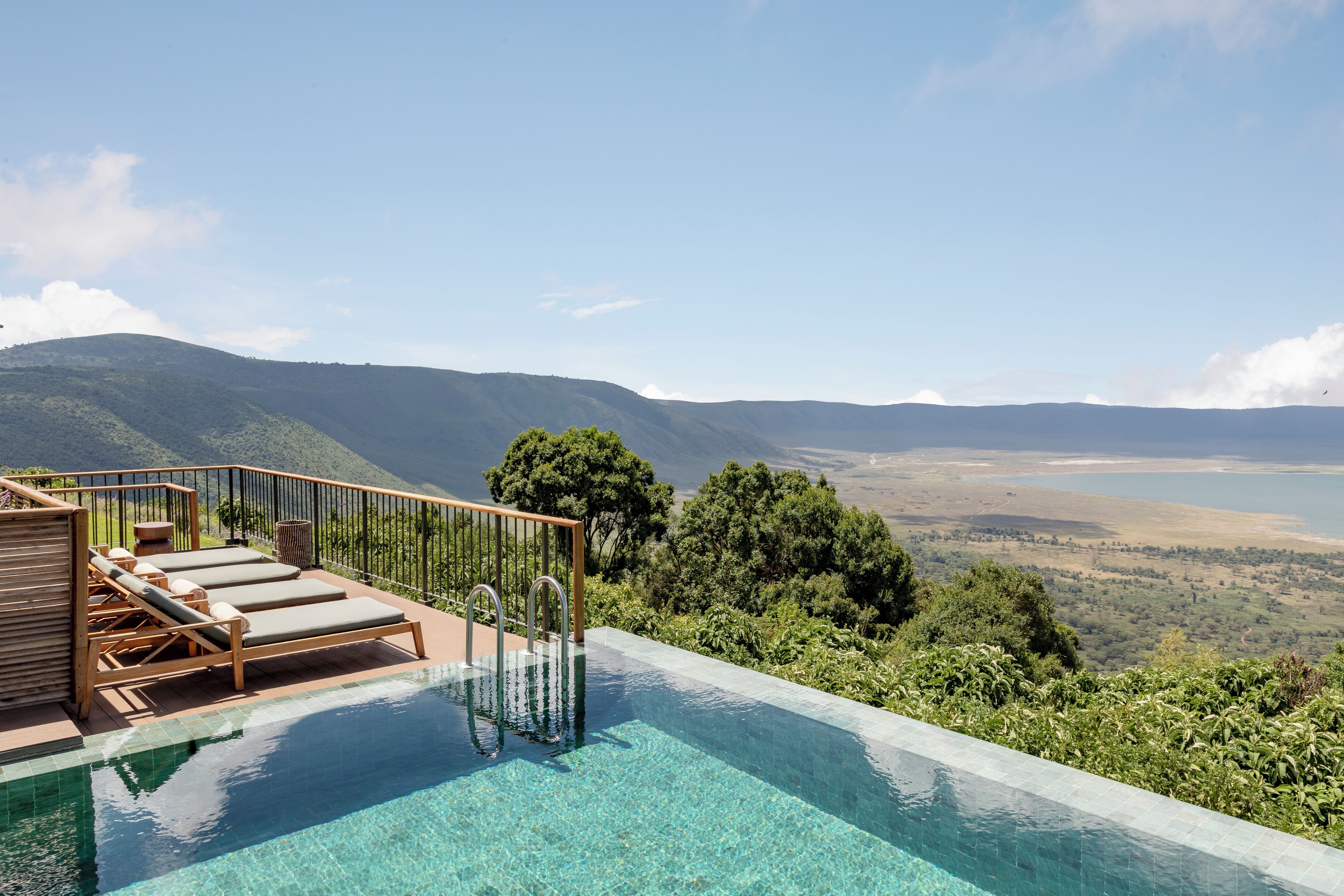 Piscina com água cristalina, deck de madeira e espreguiçadeiras.