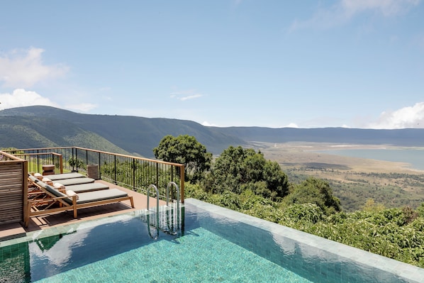 A pool with clear water, wooden deck, and lounge chairs. - Ngorongoro Lodge Melia Collection (Ngorongoro)