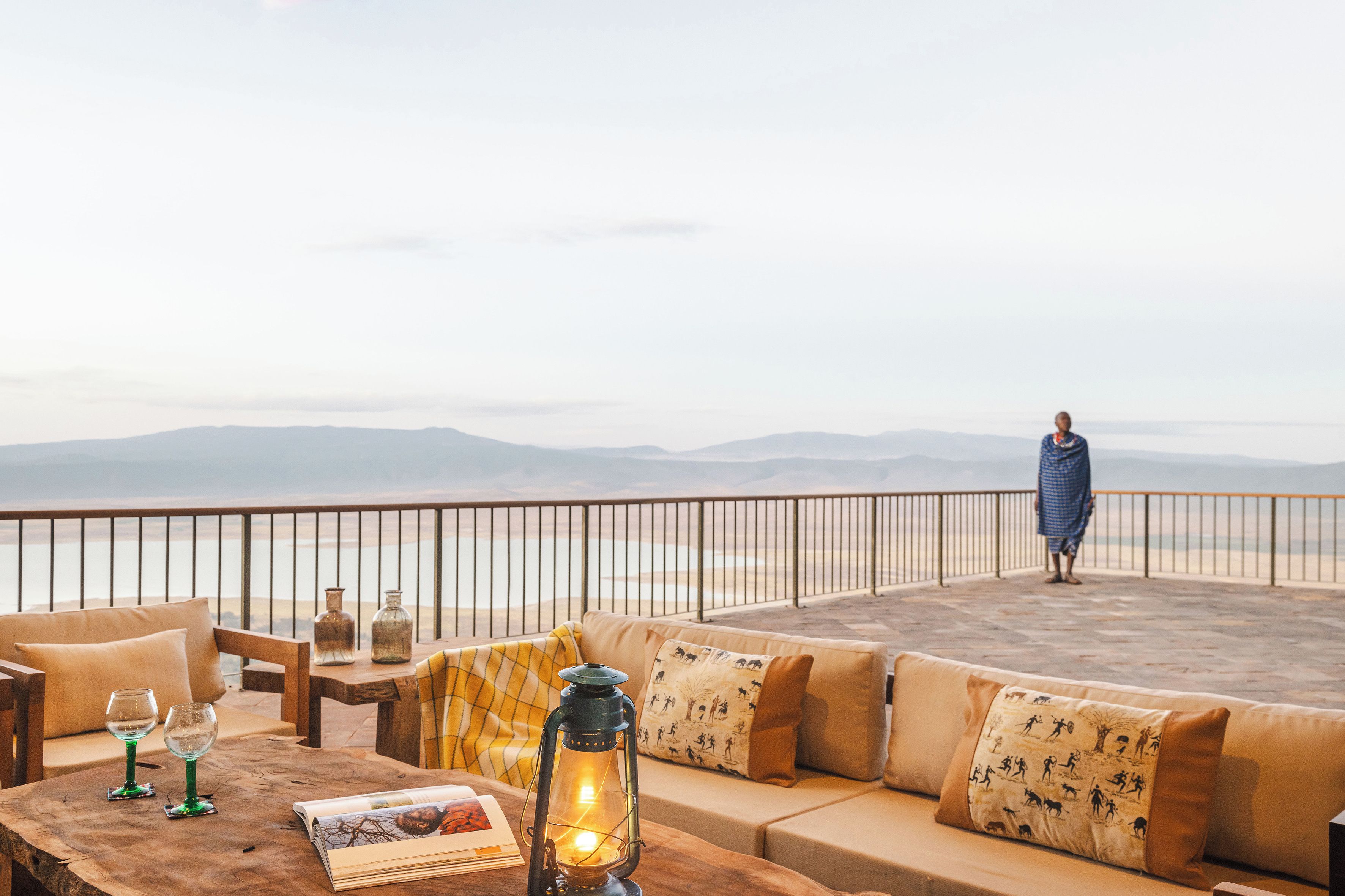 A terrace with a sofa, a wooden table, and a lantern.