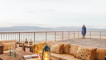 A terrace with a sofa, a wooden table, and a lantern.