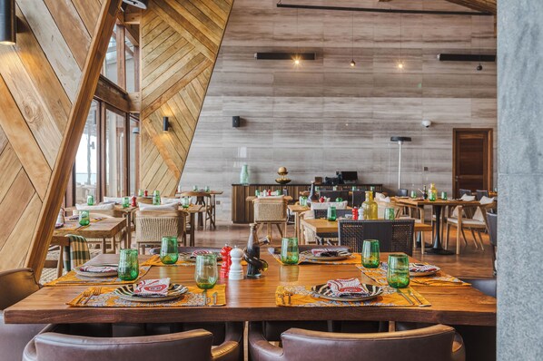 Un restaurante con mesas y sillas de madera, dispuesto con platos, vasos y cubiertos.