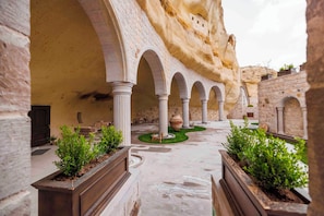 An interior courtyard with arches, columns, and planters. - Signature Cave Cappadocia Trademark Col by Wyndham (Ürgüp)
