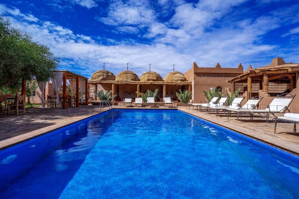 Piscina com espreguiçadeiras e um pavilhão com cúpulas.