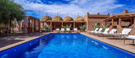 Piscina com espreguiçadeiras e um pavilhão com cúpulas.