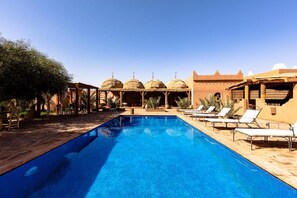 A swimming pool with lounge chairs, a covered seating area, and traditional architecture. - Abdelkhaled Benalila (M'Hamid El Ghizlane)