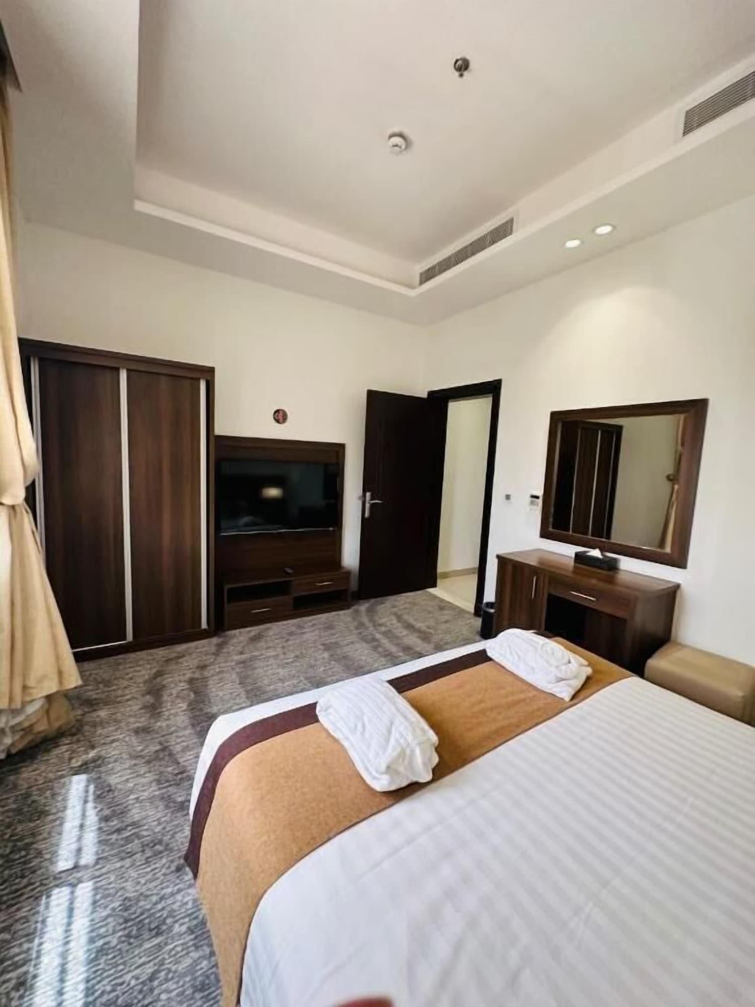 Een hotelkamer met een groot bed, een televisie, een kledingkast, een spiegel en een vloerbedekking.