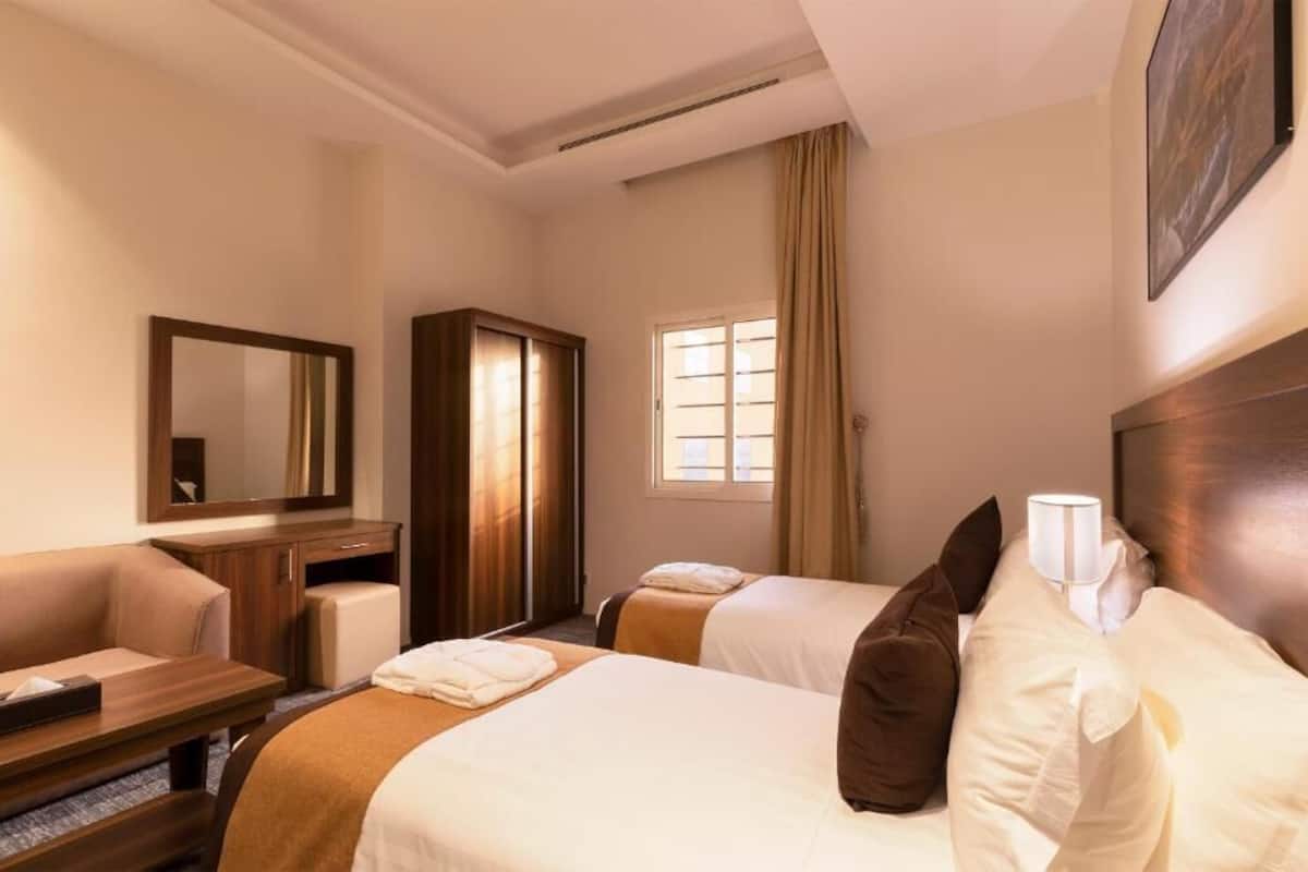 Habitación de hotel con dos camas, un escritorio, un armario y una ventana con cortinas.