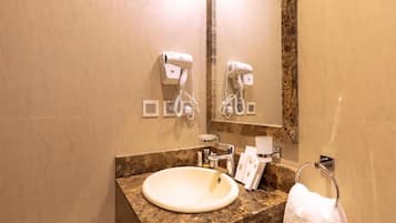 A bathroom with a marble sink, a towel rack, and two hair dryers mounted on the wall.