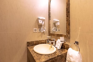 A bathroom with a marble sink, a towel rack, and two hair dryers mounted on the wall. - Seiba Hotel (Riyadh)