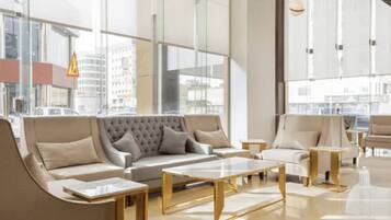 Een moderne hotelentree met een grote bank, fauteuils en een salontafel.