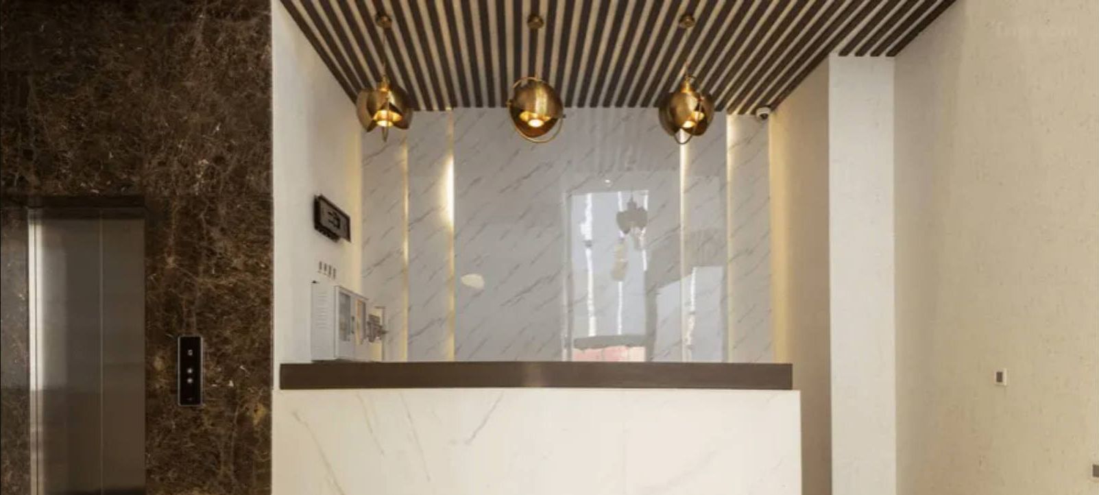 Een moderne lift met een marmeren wand en een bedieningspaneel.