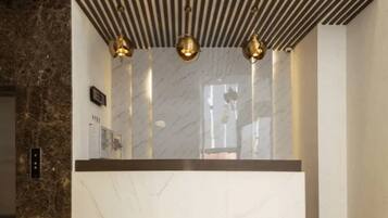 Een moderne lift met een marmeren wand en een bedieningspaneel.