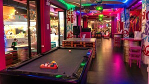 A pool table with balls, a bar area, and a seating space with tables and chairs.
