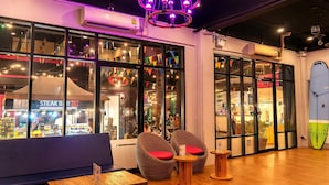 A restaurant with wicker chairs, a wooden table, and a surfboard decoration.