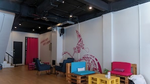 A room with a wooden floor, a red curtain, blue and red chairs, a yellow table, and a wall with a red mural.