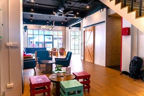 A modern interior with a wooden floor, a staircase, and a seating area with chairs and tables. - Slumber Party Surf Kata (Karon)