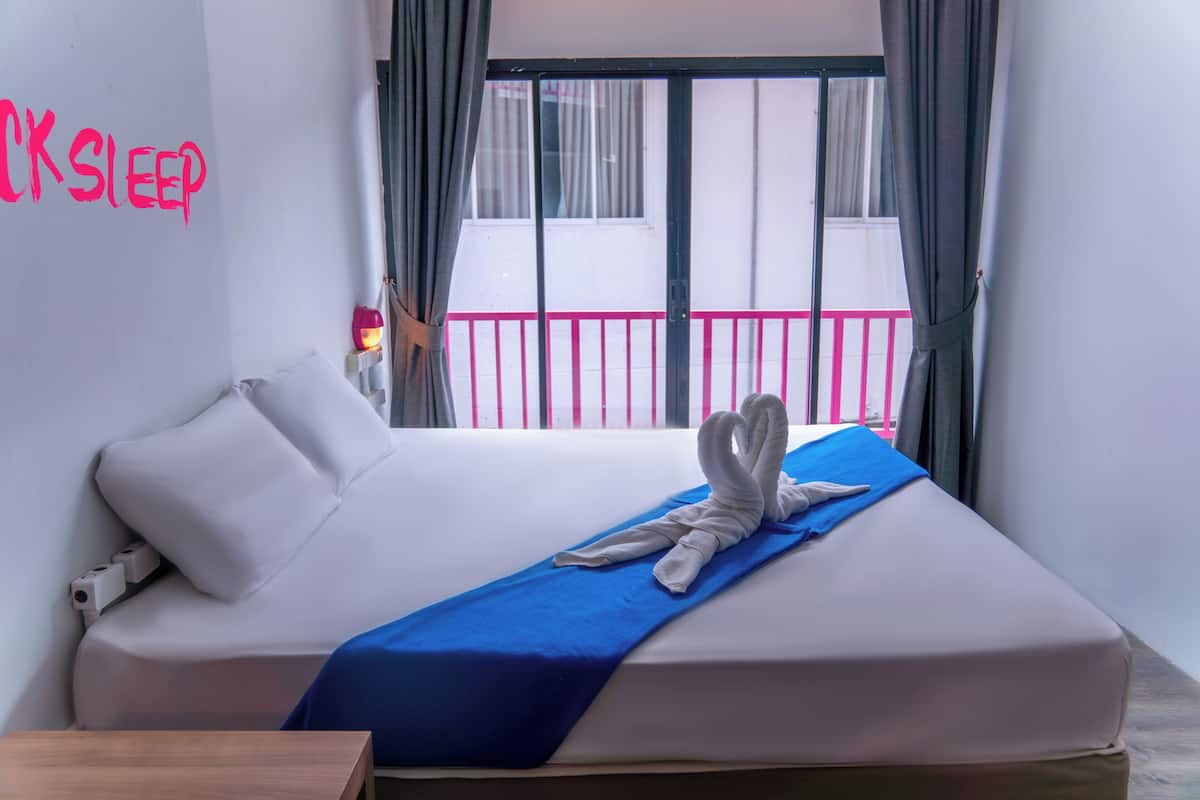 Una habitación de hotel con una cama, una colcha azul y una toalla sobre la cama.