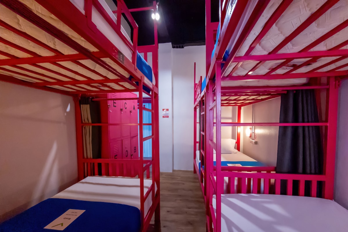 A room with bunk beds, a blue bedspread, and a white wall with a door.