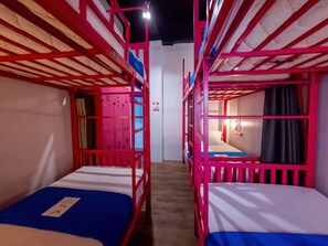 A room with bunk beds, a blue bedspread, and a white wall with a door.