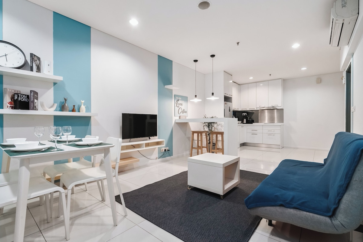 Una sala de estar moderna con comedor, cocina y televisor.
