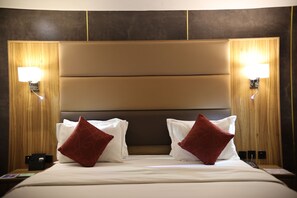 Une chambre d’hôtel avec un grand lit, deux lampes de chevet et une tête de lit en bois.