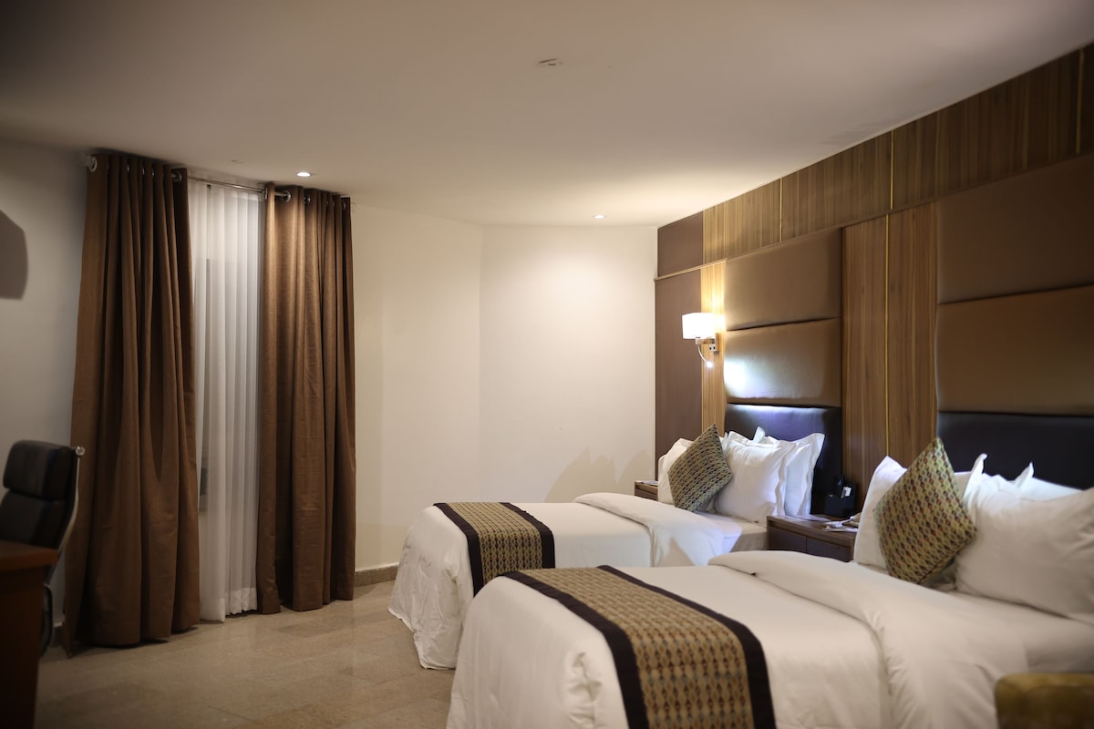 Habitación de hotel con dos camas, un escritorio y una silla.